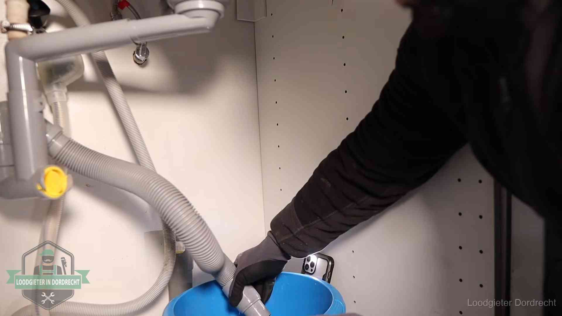 Afvoerslang loopt leeg in een emmer onder de gootsteen in Dordrecht, een klus die je zelf kunt doen