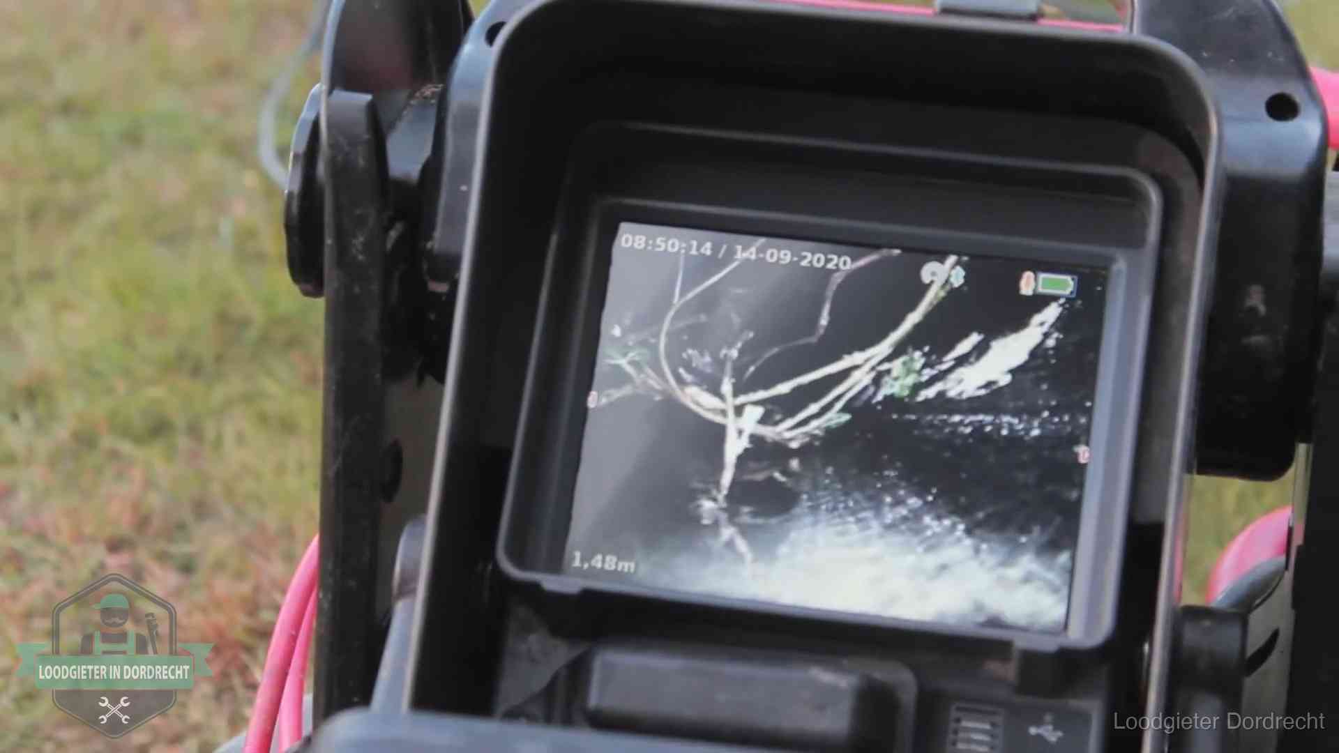 Monitor van een rioolcamera toont wortelingroei in de rioolbuis bij een woning in Dordrecht
