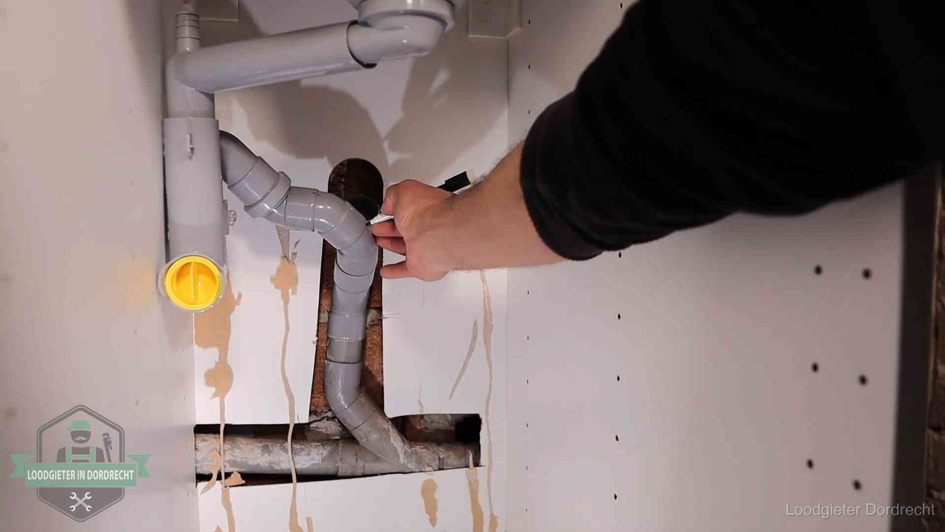 Loodgieter markeert een pvc-afvoerbuis onder een gootsteen in Dordrecht