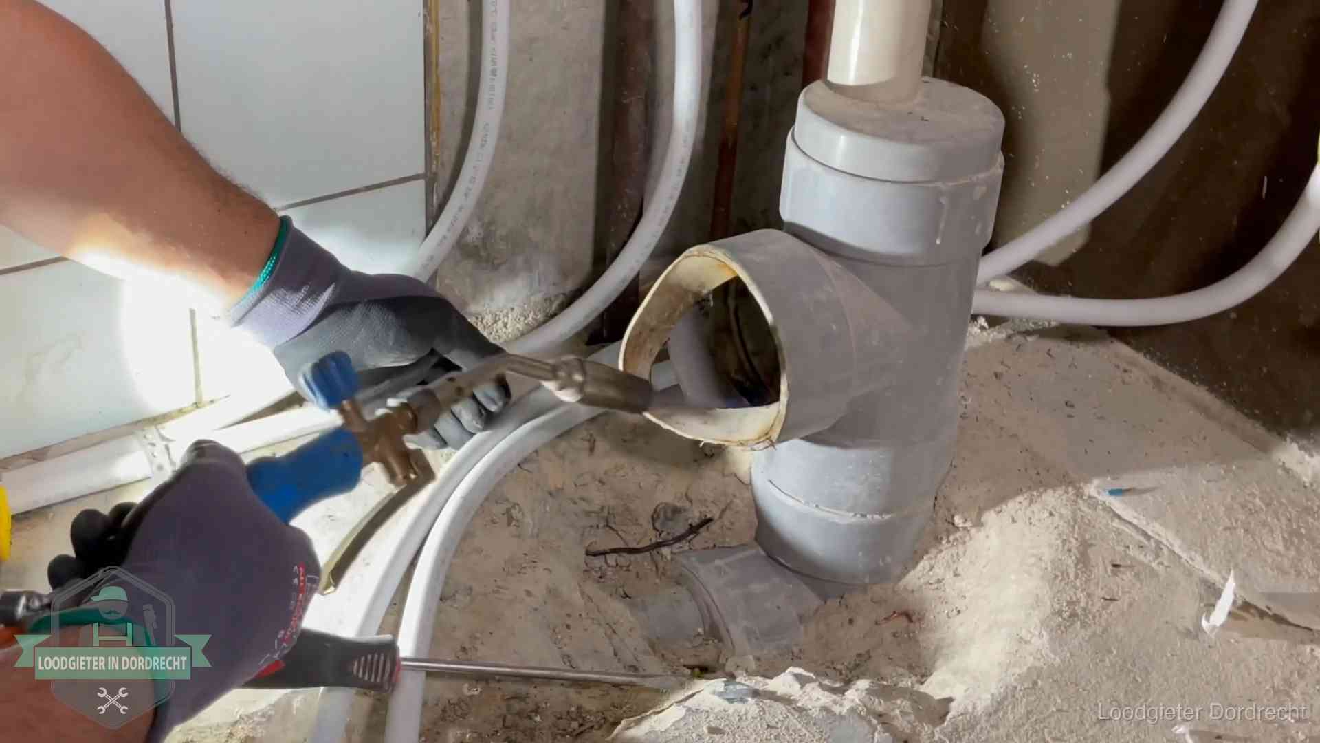 Loodgieter werkt met brander en messing kraanwerk aan leidingen in Dordrecht