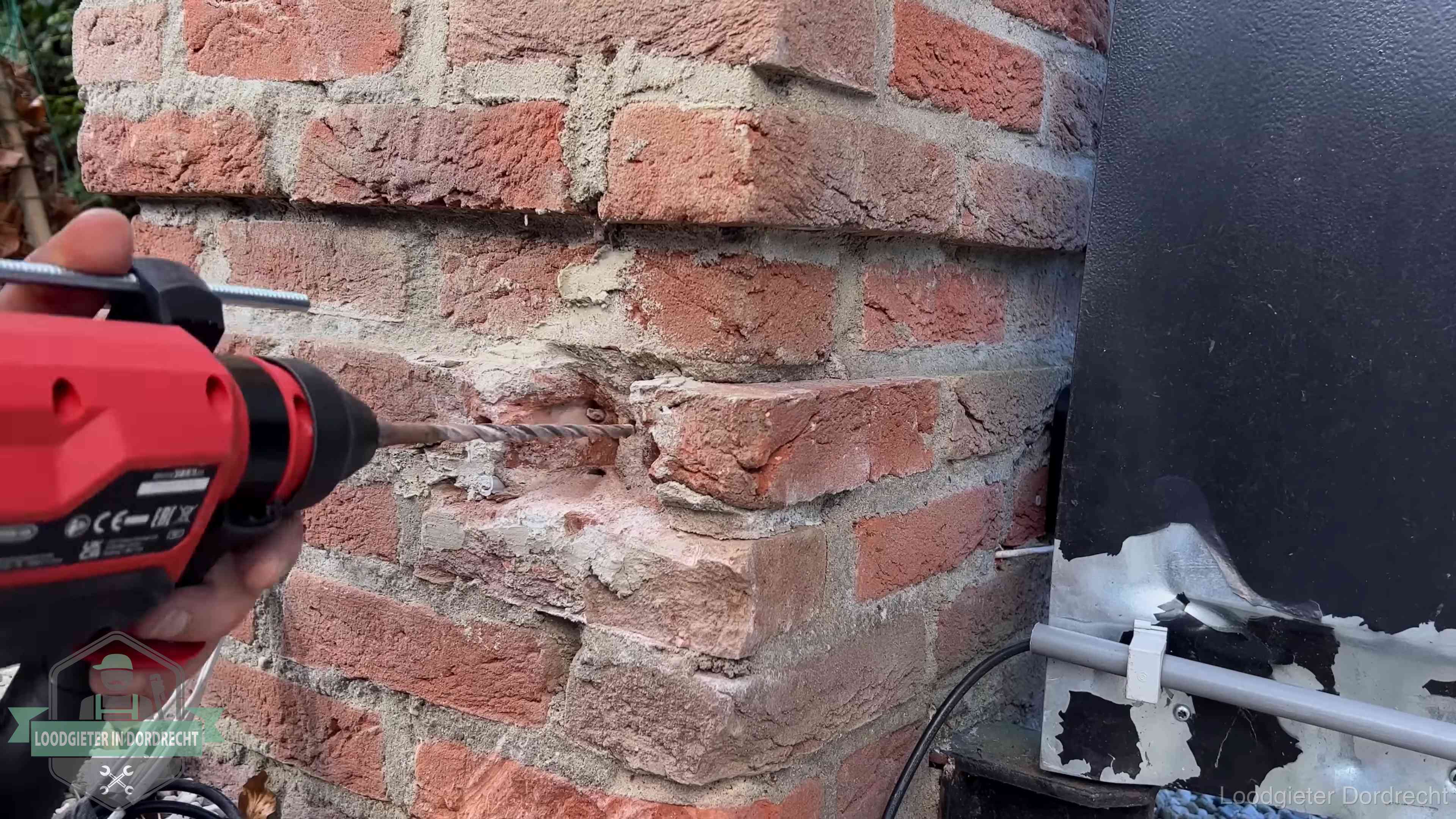 Vakman boort in de buitenmuur van een woning in de regio Dordrecht