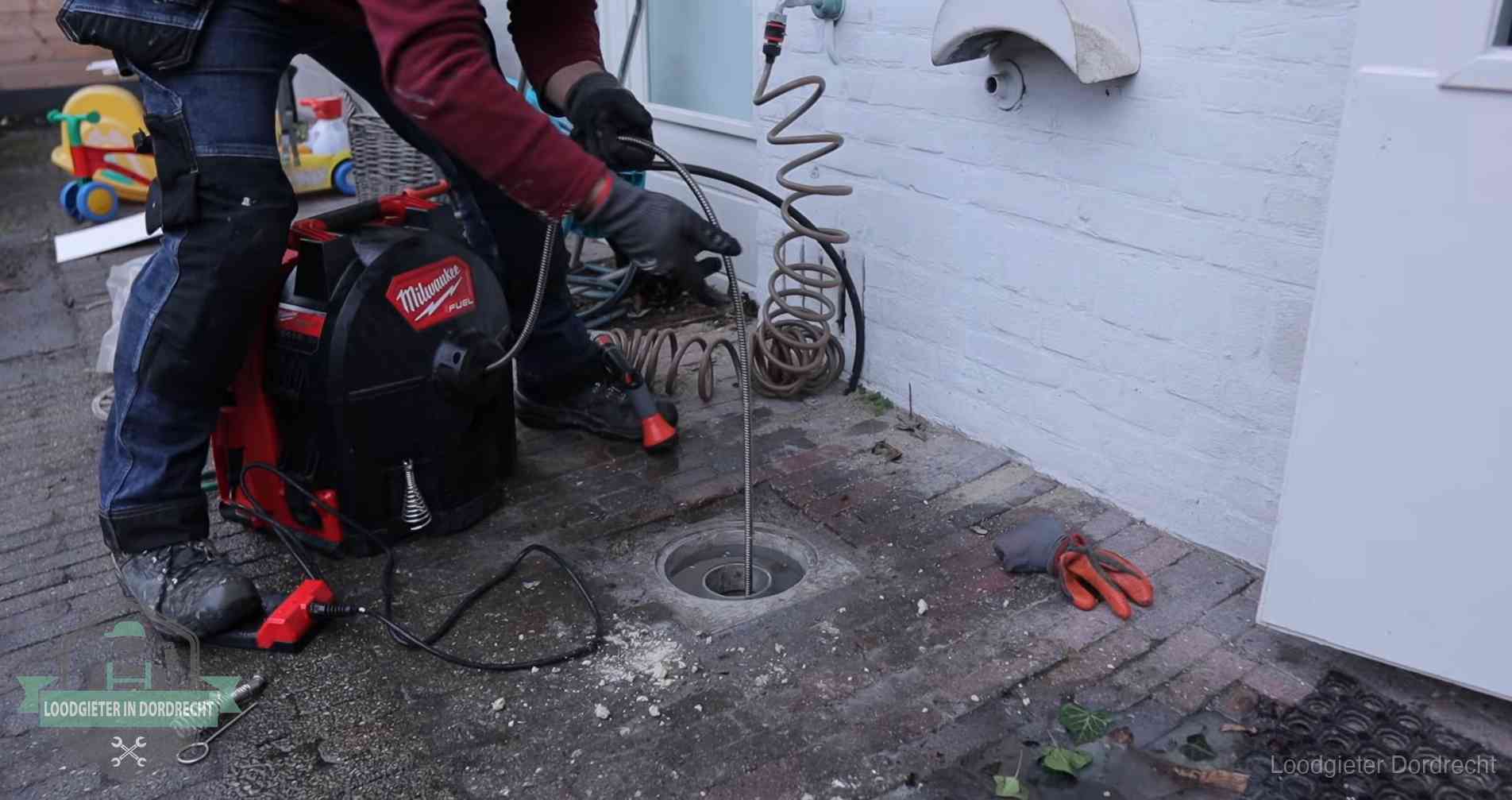 Ontstoppingsputje in de bestrating naast de gevel van een woning in Dordrecht