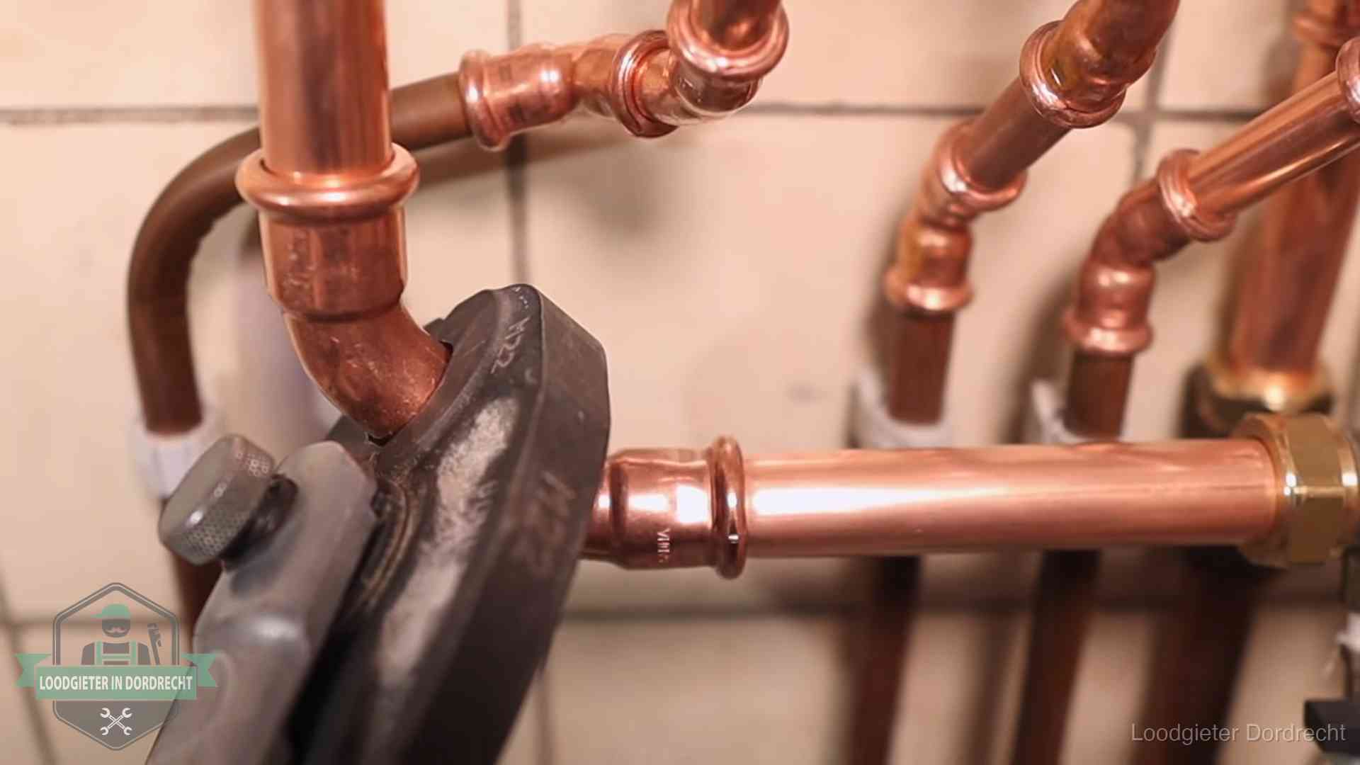 Persmachine perst een koperen fitting op nieuw leidingwerk in Dordrecht