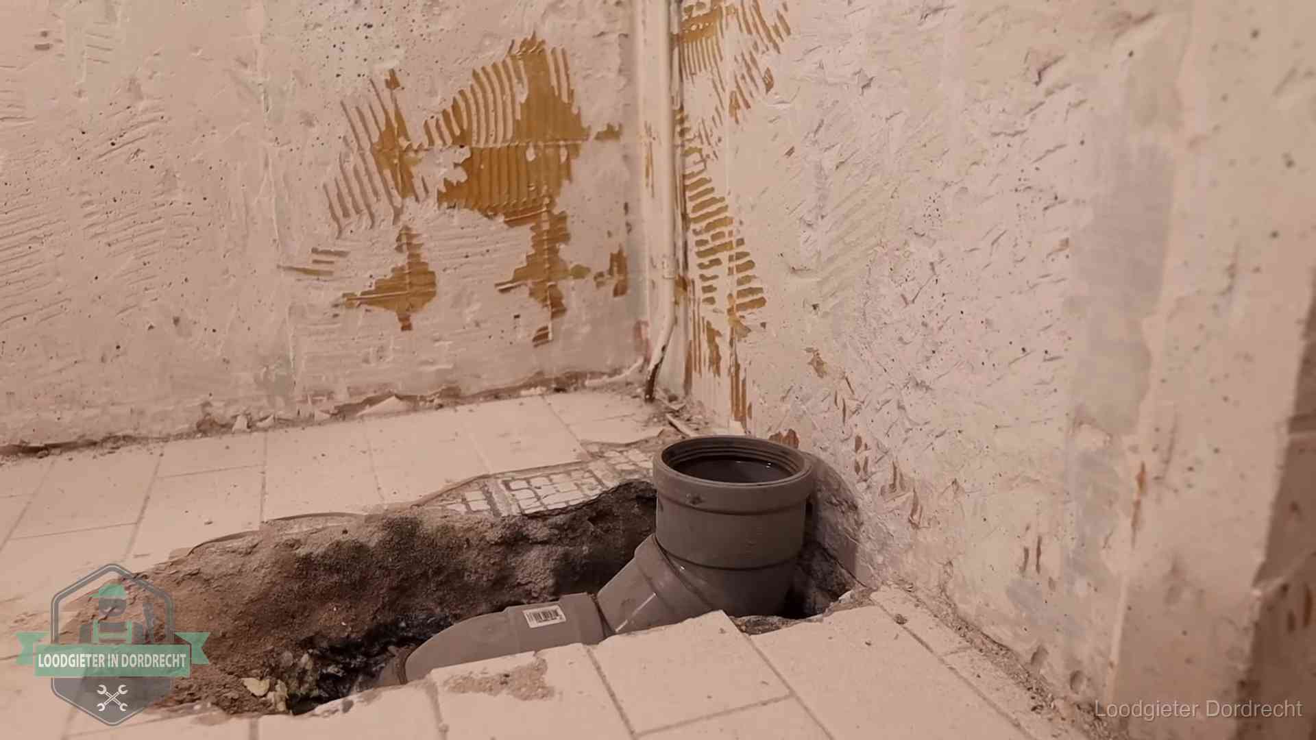 Opengebroken vloer met een nieuwe pvc-rioolbocht in een gegraven sleuf in Dordrecht