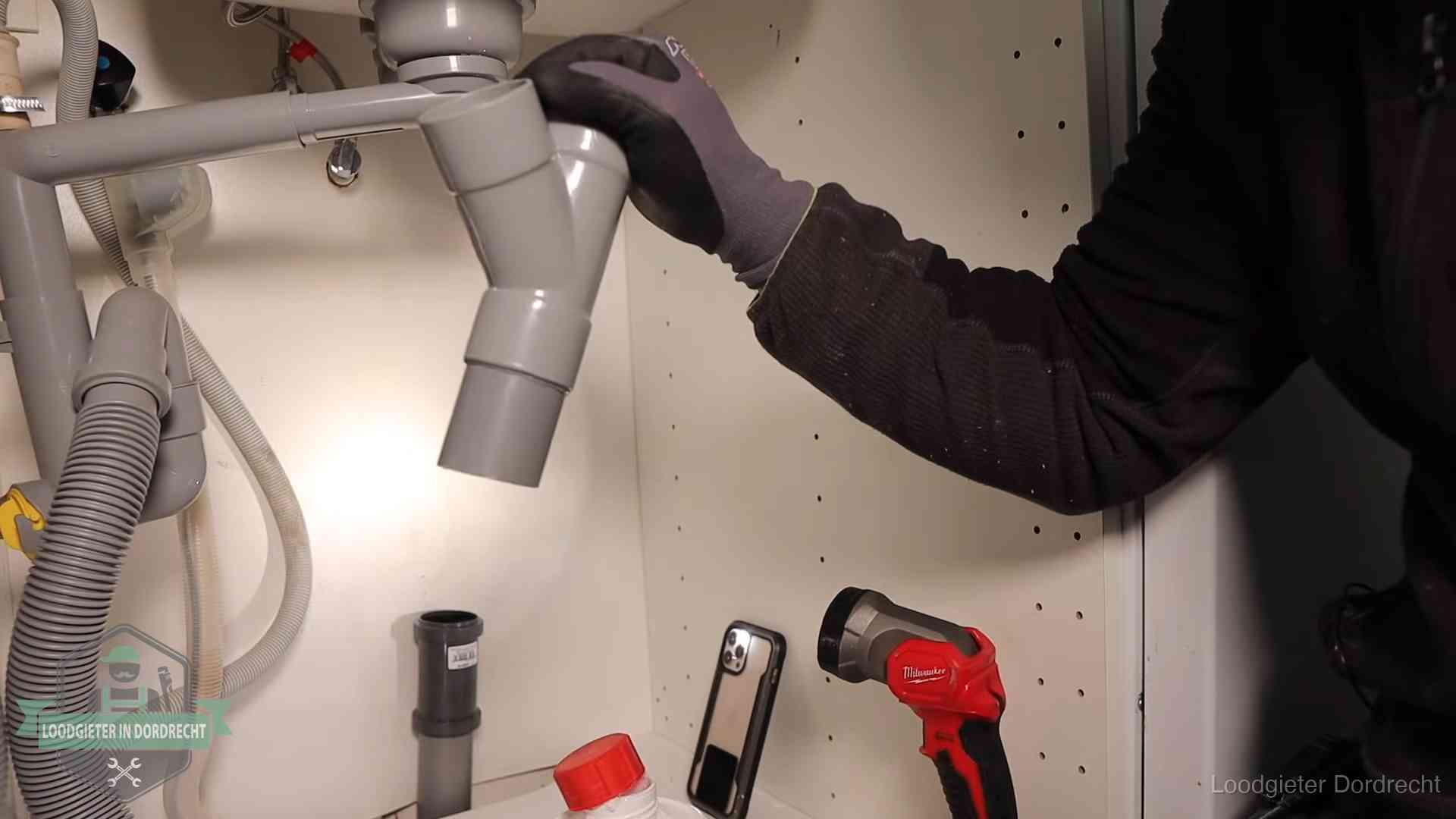 Loodgieter demonteert het sifon- en afvoerwerk onder een gootsteen in Dordrecht bij stankklachten