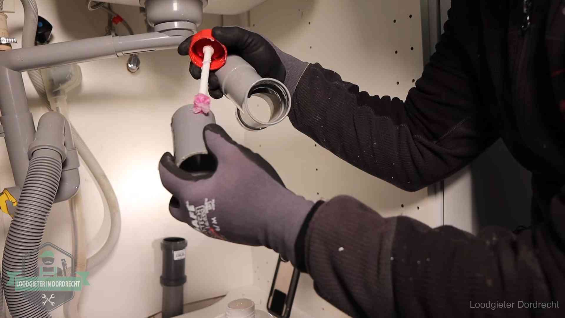 Loodgieter demonteert en reinigt de sifon onder een keukenkast in Dordrecht
