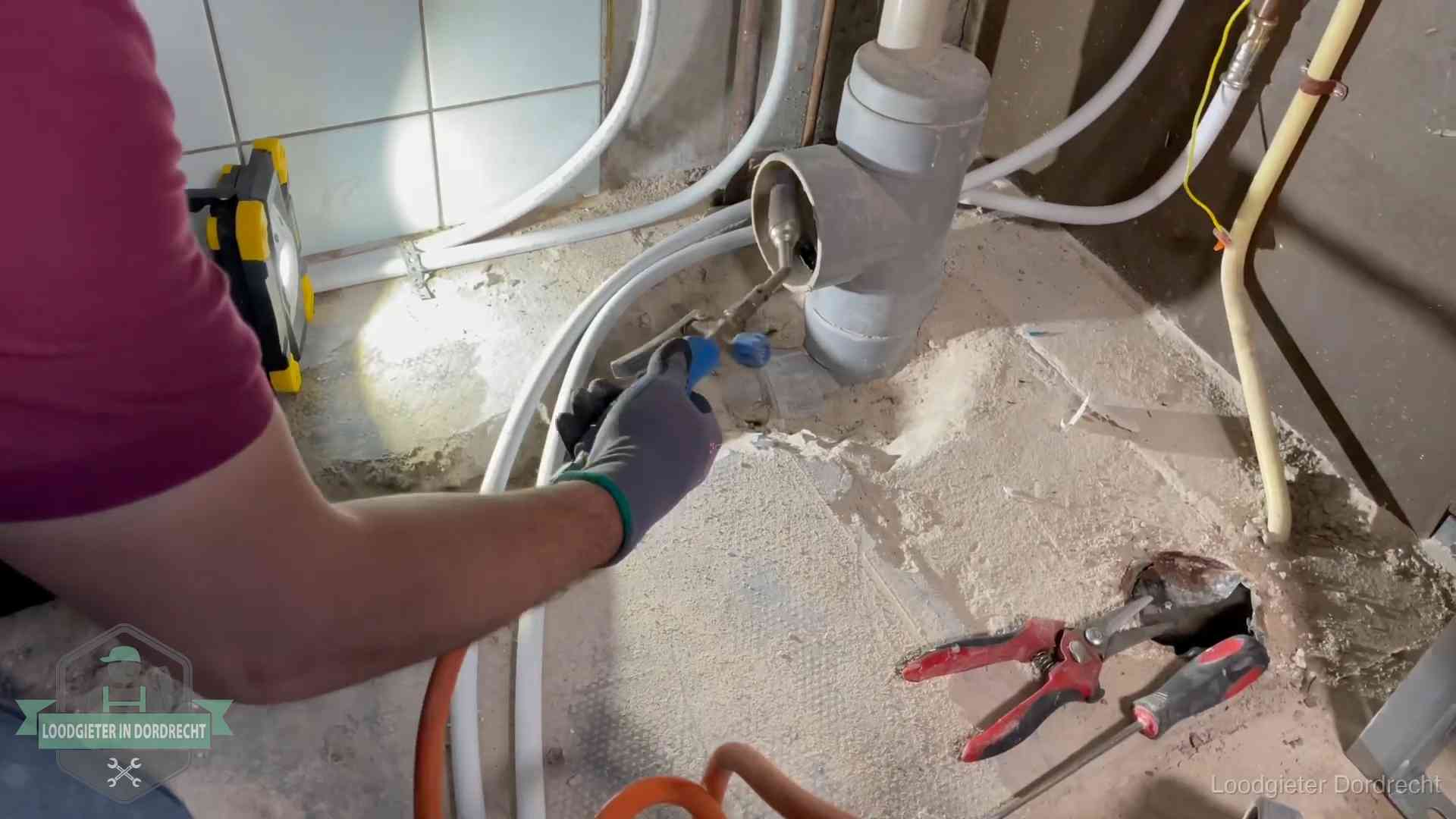 Loodgieter werkt aan leidingen bij een pvc-standleiding in een appartement in Dordrecht